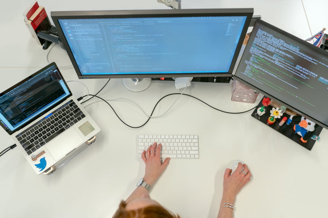 A software engineer coding on three computer screens.